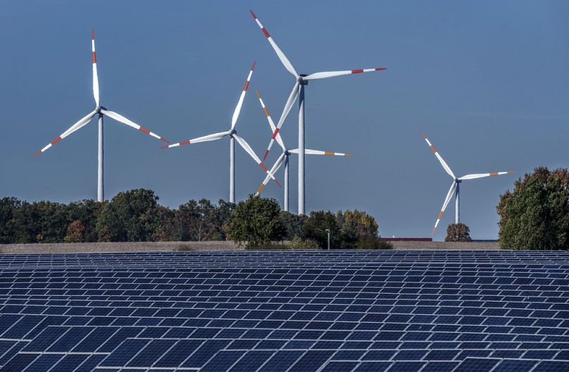 Turbiny wiatrowe skręcają za farmą fotowoltaiczną w Rapshagen w Niemczech.