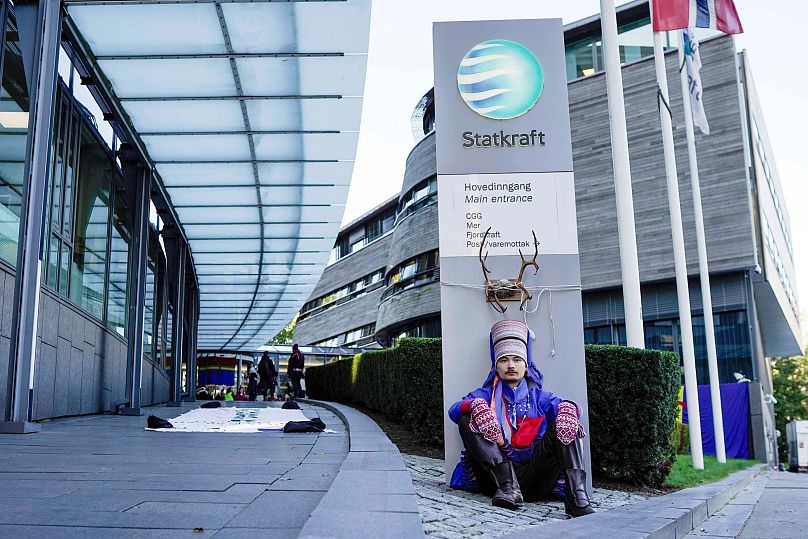 Aktywista Mihkkal Hætta ma na sobie tradycyjny lapoński strój i protestuje przed wejściem do Statkraft – państwowej firmy obsługującej 80 turbin wiatrowych.