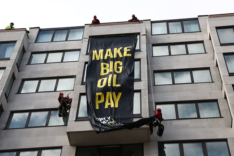 Aktywiści Greenpeace rozwijają baner z napisem „Make Big Oil Pay”  z dachu InterContinental London Park Lane podczas wydarzenia „Oily Money Out”  demonstracja.