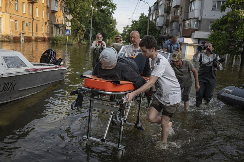Wolontariusze niosą na noszach kobietę ewakuowaną z zalanej dzielnicy lewego brzegu Dniepru w Chersoniu, czerwiec 2023 r.