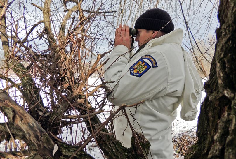 rumuński policjant graniczny obserwujący przez lornetkę ziemię niczyją między Ukrainą a Rumunią w pobliżu Halmeu, styczeń 2013 r.