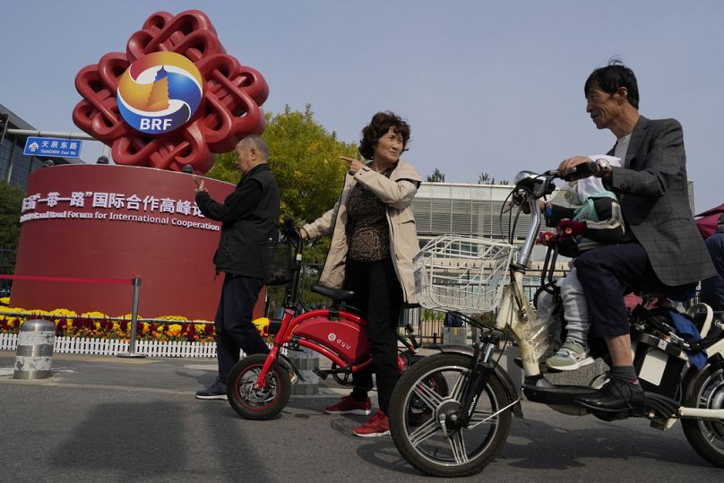 Mieszkańcy mijają logo Forum Pasa i Szlaku przed Chińskim Narodowym Centrum Kongresowym w Pekinie, październik 2023 r
