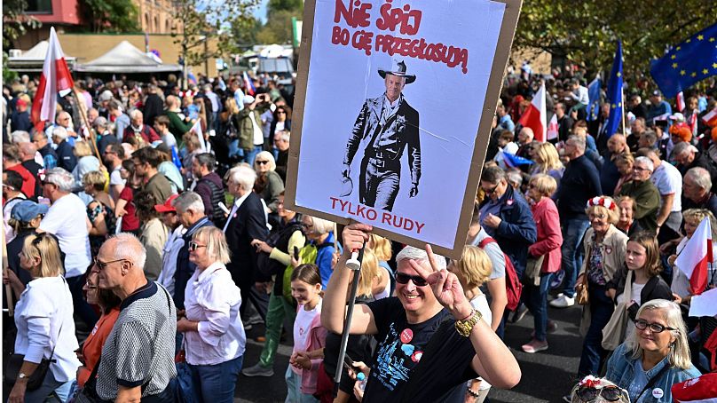 Mężczyzna pokazuje plakat z liderem opozycji Donaldem Tuskiem w roli marszałka USA i napisem: „Nie śpij, bo cię przegłosują”.