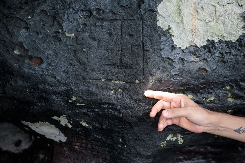 Archeolog Jaime de Santana Oliveira wskazuje na starożytną rzeźbę w kamieniu, odsłoniętą po tym, jak poziom wody spadł do rekordowo niskiego poziomu podczas suszy w Manaus, 23 października.