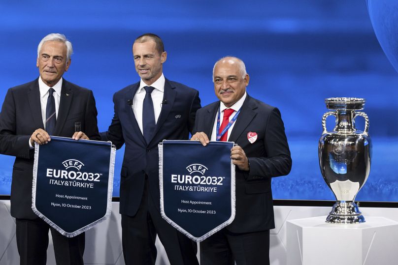 Prezydent UEFA Aleksander Ceferin (w środku) pokazuje nazwę Włoch i Turcji wybranych na gospodarzy turnieju piłkarzyków Euro 2032