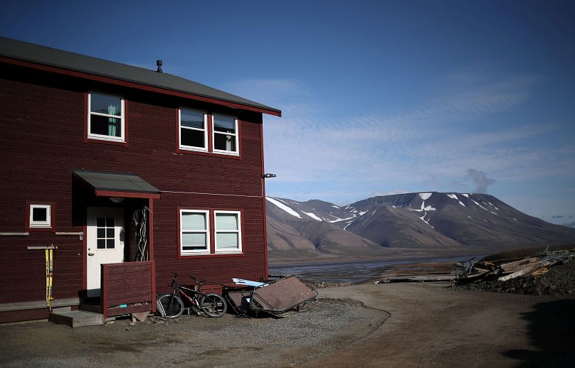 Dom mieszkalny widać przed ośnieżonymi górami w miejscowości Longyearbyen na Svalbardzie w Norwegii.