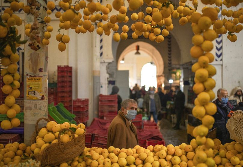 Mężczyzna przechodzi obok straganu z cytrynami na rynku centralnym w Tunisie, styczeń 2021 r