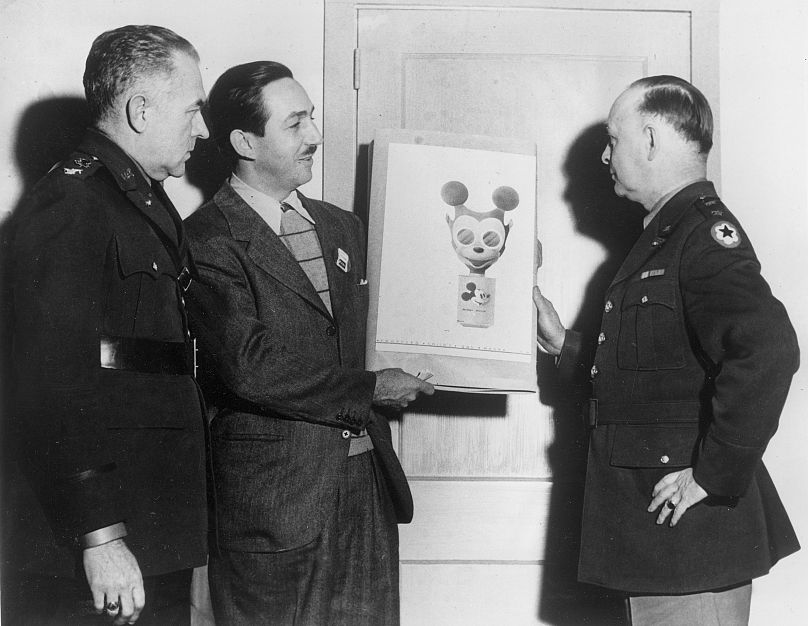 Walt Disney, drugi od lewej, przekazuje swój szkic maski gazowej Myszki Miki generałowi dywizji Williamowi Porterowi (z prawej) w Waszyngtonie, 8 stycznia 1942 r.