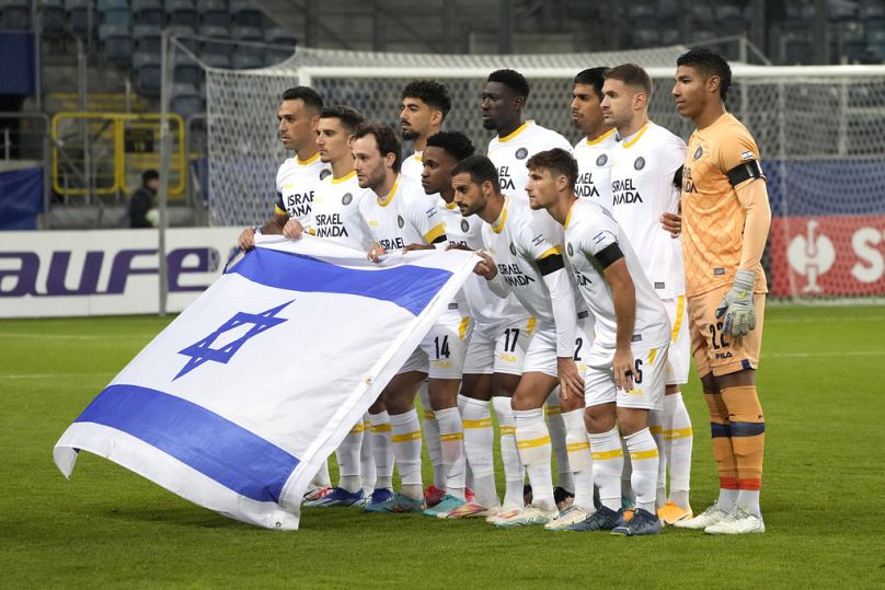 Gracze Maccabi Tel Aviv pokazują izraelską flagę, pozując do oficjalnego zdjęcia przed meczem piłki nożnej grupy B Ligi Konferencji Europejskiej pomiędzy Zoryą Ługańsk i Maccabi Te