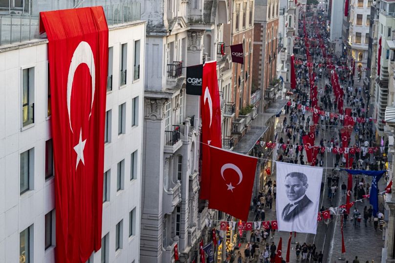 Tureckie flagi narodowe i baner przedstawiający Mustafę Kemala Ataturka, ojca założyciela Republiki Turcji, wywieszone na alei Istiklal w Stambule, październik 2023 r.