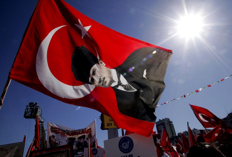 Demonstranci machają tureckimi flagami i flagą z wizerunkiem założyciela współczesnej Turcji Ataturka podczas prosekularnego wiecu w Izmirze, maj 2007