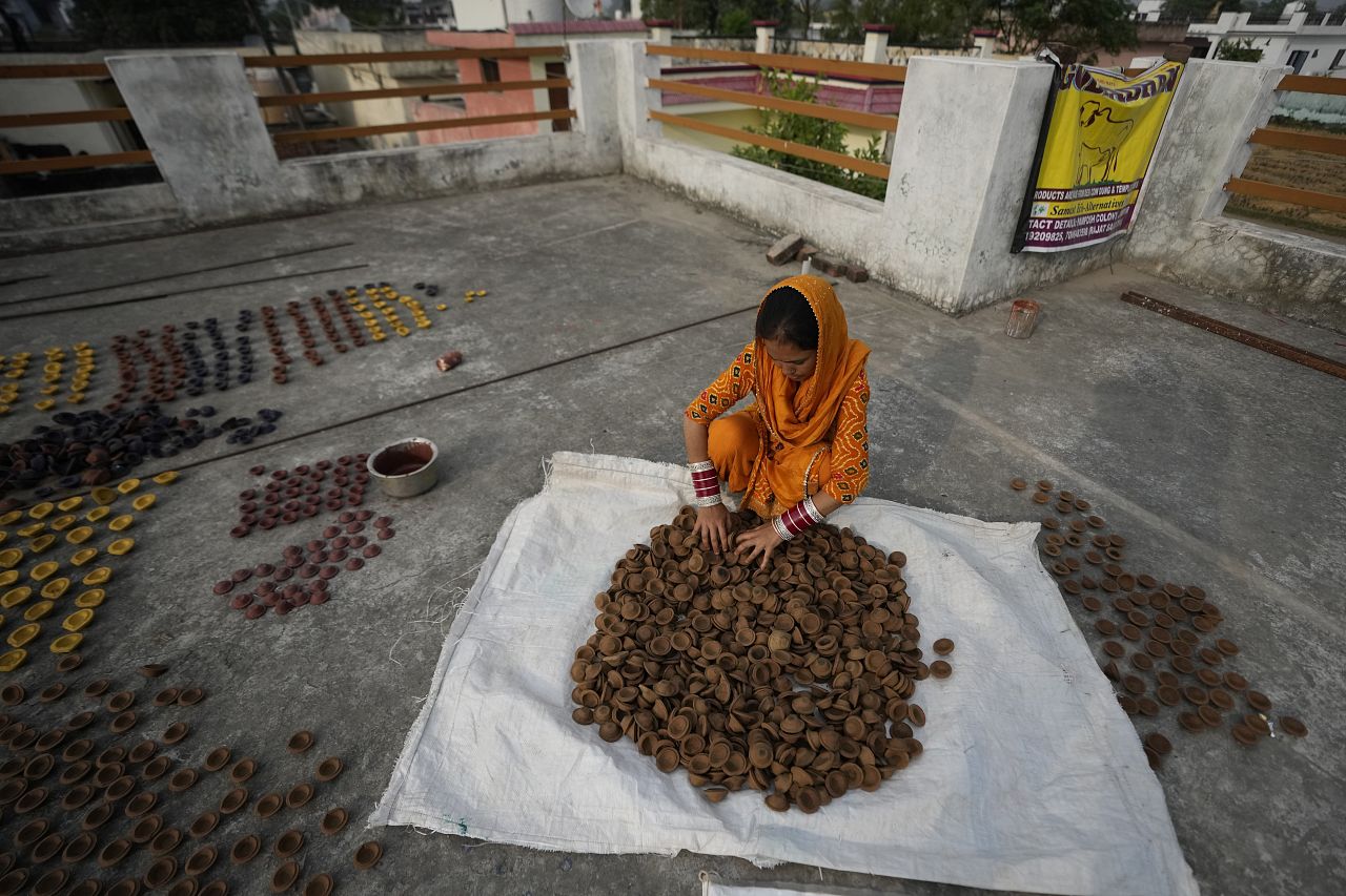 Kobieta przygotowuje lampy wykonane z krowiego łajna przed Diwali w Dżammu w Indiach, wtorek, 7 listopada 2023 r.