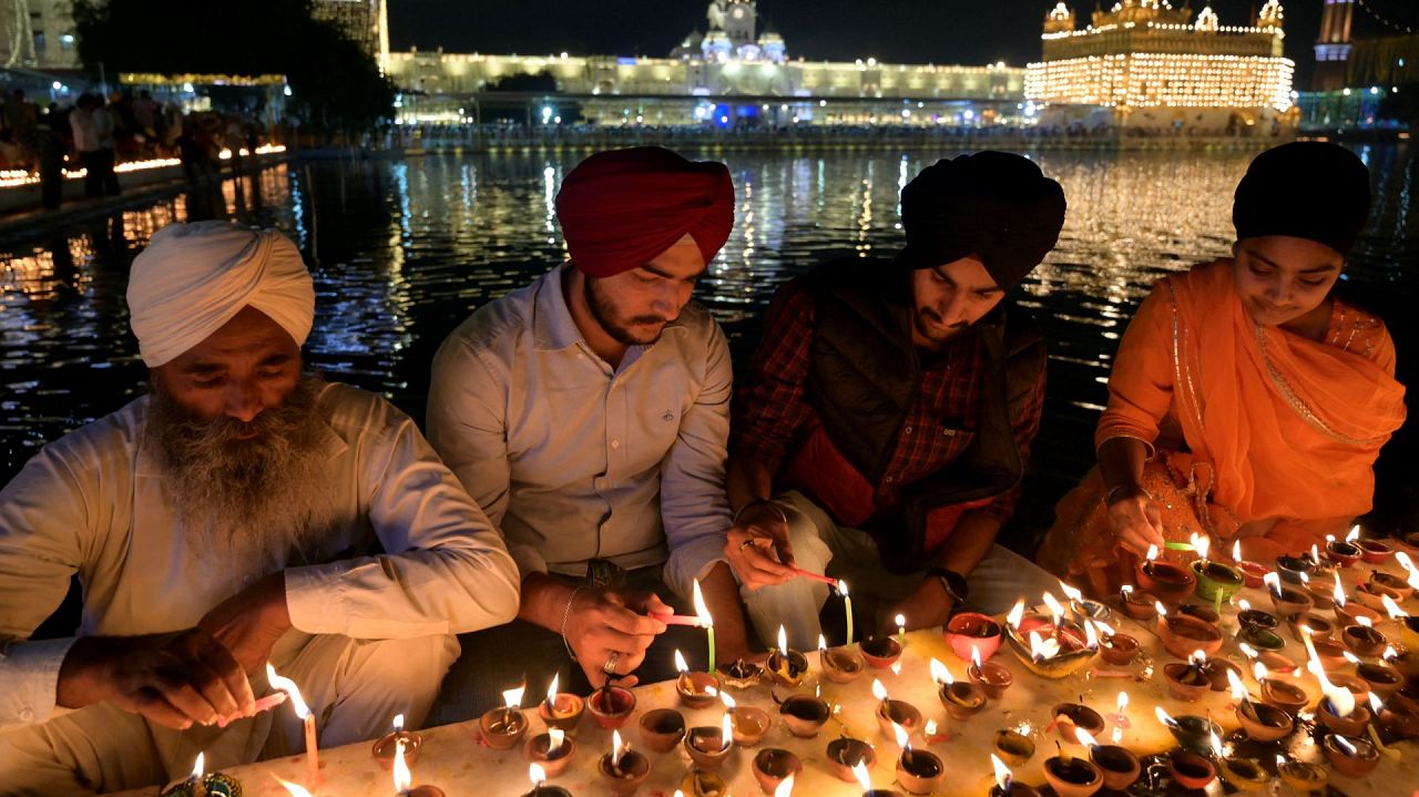 Wielbiciele sikhijscy zapalają lampy oliwne z okazji festiwalu sikhijskiego Bandi Chhor Divas lub festiwalu Diwali w oświetlonej Złotej Świątyni w Amritsar, 12 listopada 2023 r.