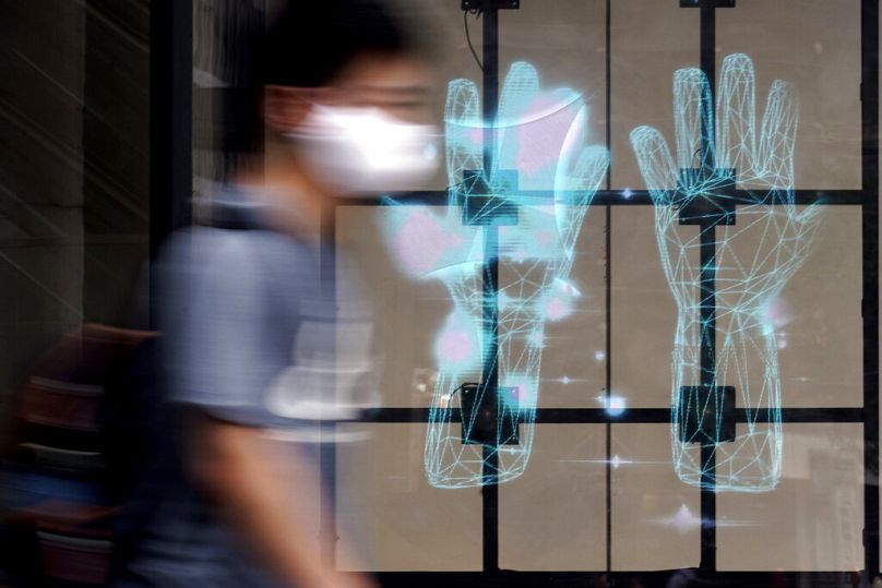 Mężczyzna w masce chroniącej przed rozprzestrzenianiem się nowego koronaawirusa przechodzi obok publicznego ogłoszenia o konieczności mycia rąk w Tokio, lipiec 2020 r.