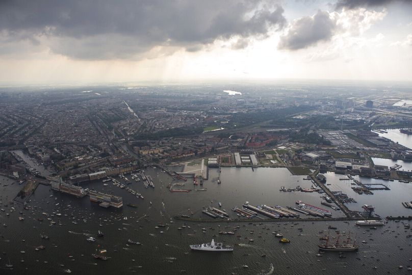 Wysokie statki eskortowane przez małe łodzie przybywają do Amsterdamu, sierpień 2015 r