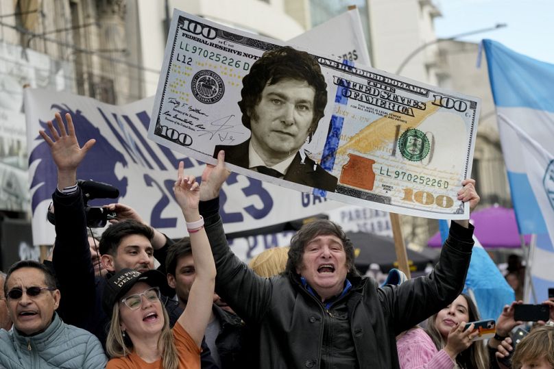 Javier Milei trzyma gigantyczny karton przedstawiający banknot 100 dolarów z wizerunkiem jego twarzy podczas wiecu w La Plata w Argentynie, wtorek, 12 września 2023 r.