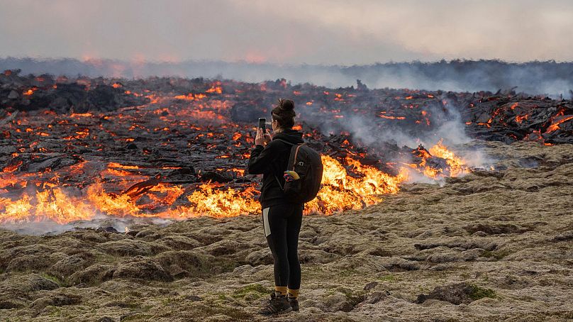 Osoba spaceruje w pobliżu lawy wydobywającej się ze szczeliny wulkanu Fagradalsfjall w pobliżu góry Litli-Hrútur, 10 lipca 2023 r.