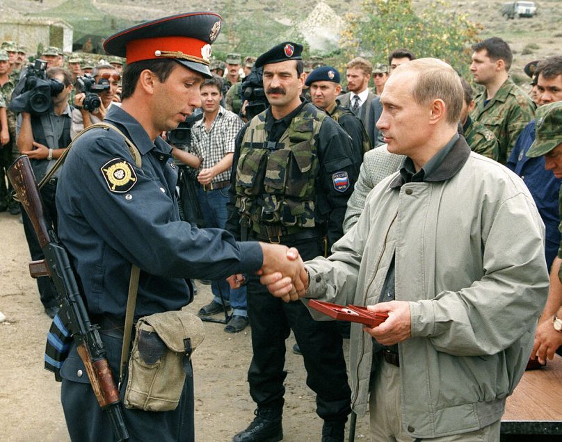 Premier Rosji Władimir Putin (z prawej) wręcza nagrodę miejscowemu funkcjonariuszowi policji w rosyjskiej bazie wojskowej w górach regionu Botlich, sierpień 1999 r.