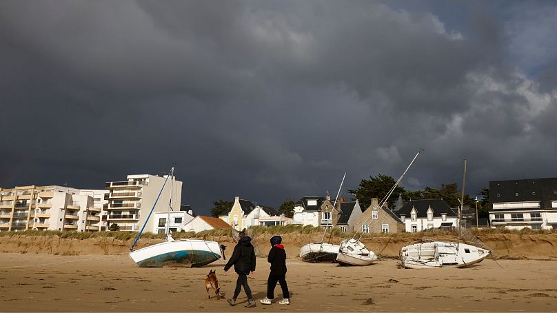 Para spaceruje z psem łodziami wyrzuconymi na brzeg na plaży Pornichet w Bretanii, czwartek, 2 listopada 2023 r.