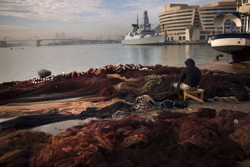 Rybak naprawia sieć w porcie rybackim w Barcelonie, czerwiec 2012 r