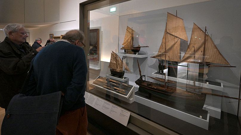 Ludzie oglądają modele zabytkowych łodzi rybackich wystawione we francuskim muzeum marynarki wojennej w Paryżu, 16 listopada 2023 r.