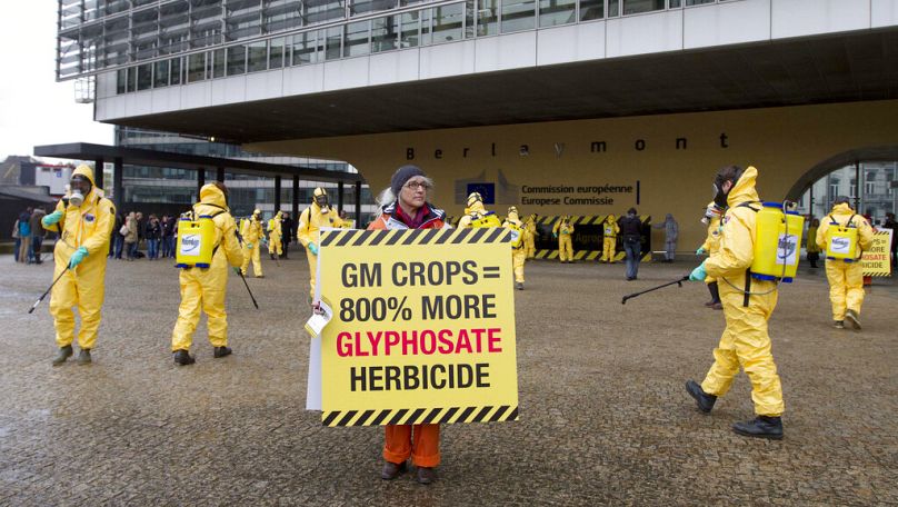 Członkowie Greenpeace noszą udane kombinezony zawierające materiały niebezpieczne i rozpylają wodę podczas demonstracji przed siedzibą UE w Brukseli, listopad 2012 r.