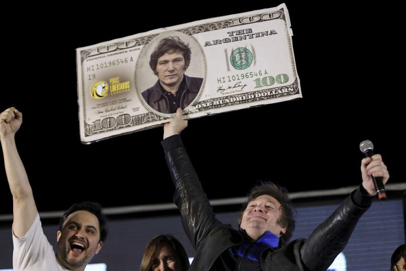 Javier Milei, kandydat na prezydenta koalicji Liberty Advances, trzyma kartonowy wizerunek banknotu 100 dolarów amerykańskiego ozdobionego wizerunkiem jego twarzy, Kordoba, listopad 2023 r.