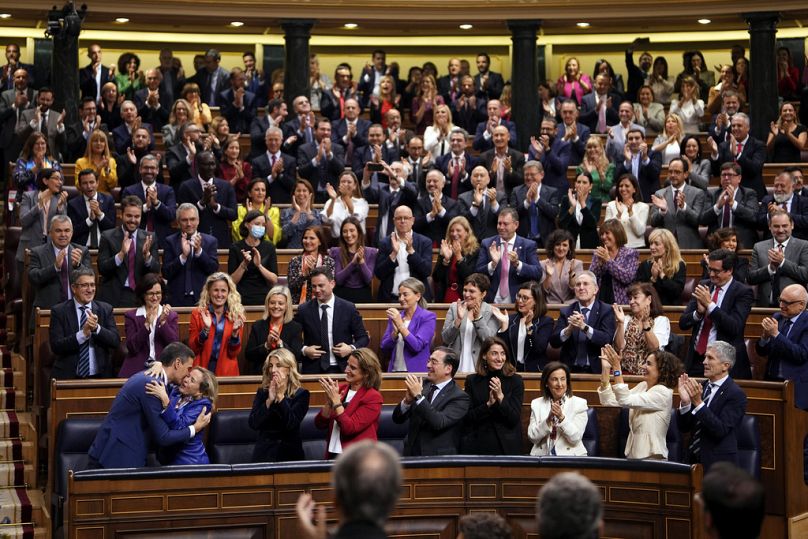 Ponownie wybrany premier Hiszpanii Pedro Sanchez (na dole po lewej stronie) obejmuje minister gospodarki i pierwszą wicepremier Nadię Calvino w hiszpańskim parlamencie w Madrycie, Hiszpania