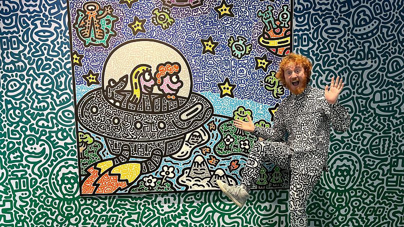 Brytyjski artysta Sam Cox, lepiej znany jako Mr. Doodle, pozuje do zdjęcia ze swoim dziełem 