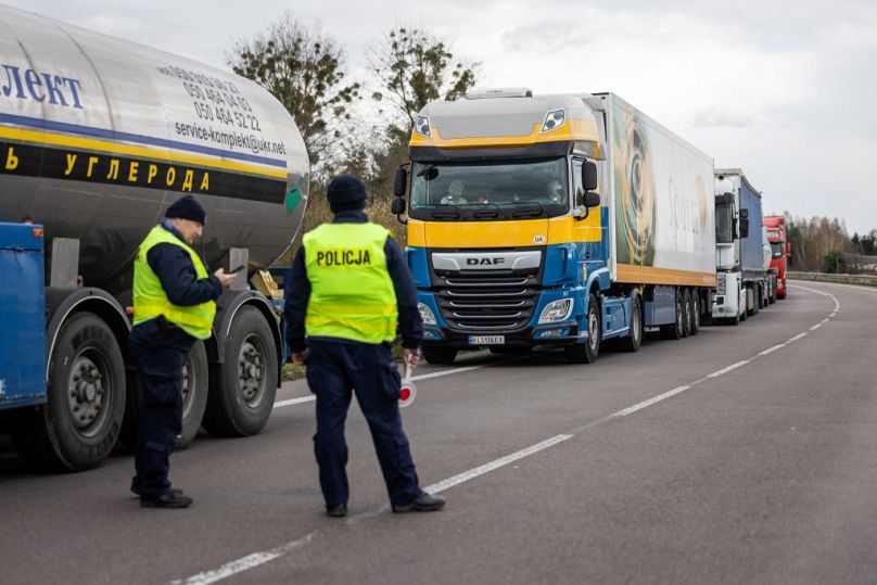 Polscy policjanci obok kolejki ciężarówek, gdy właściciele firm transportowych blokują wjazd na polsko-ukraińskie przejście graniczne w Dorohusku 6 listopada.