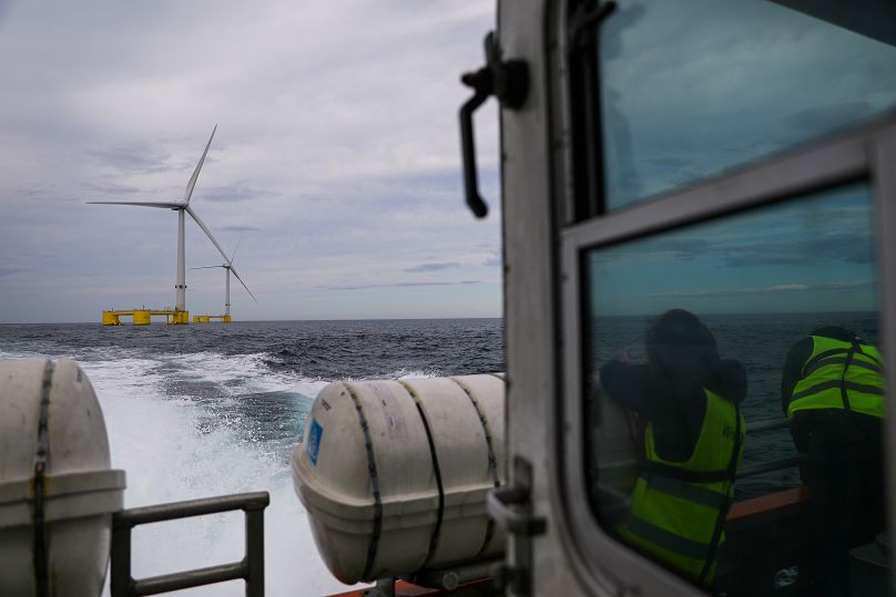 Odwiedzający na łodzi obserwują turbiny projektu WindFloat Atlantic Project, pływającej morskiej platformy generującej energię wiatrową, położonej 20 kilometrów od wybrzeża w Viana do Castelo.