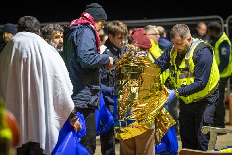 Straż przybrzeżna, personel pogotowia ratunkowego, straż graniczna i policja eskortują osoby ubiegające się o azyl, które właśnie wylądowały na plaży Dungeness na łodzi ratunkowej RNLI