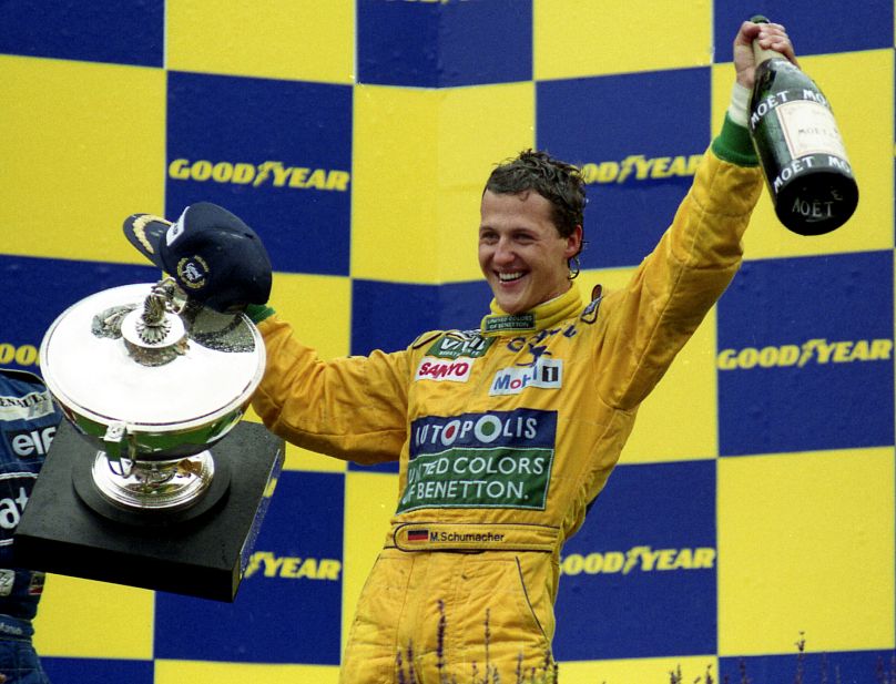 Michael Schumacher cały się uśmiecha, trzymając trofeum i butelkę magnum szampana, po wygraniu swojego pierwszego wyścigu Grand Prix na Francorchamps w Belgii, 30 sierpnia 1992 r.,