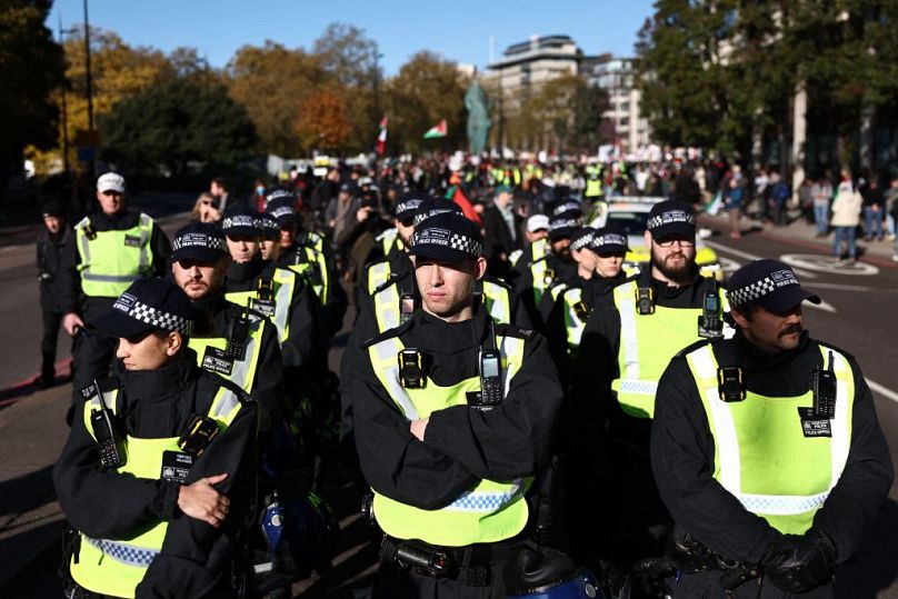 Policjant przygotowuje się do eskortowania marszu, gdy protestujący zbierają się z plakatami i flagami z okazji „Narodowego Marszu O Palestynę” w centrum Londynu w sobotę