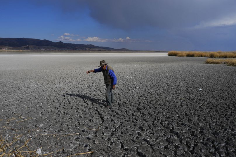 Mężczyzna spaceruje po suchym dnie jeziora Titicaca na Isla de Cojata w Boliwii, 29 września 2023 r.