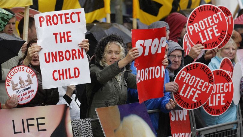 PLIK – Na tym zdjęciu z pliku z czwartku, 18 października 2012 r. protestujący sprzeciwiający się aborcji trzymają plakaty przed kliniką Marie Stopes w Belfaście w Irlandii Północnej.