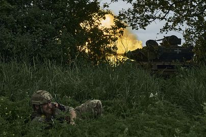 Ukraiński żołnierz leży na ziemi, gdy czołg ostrzeliwuje rosyjskie pozycje na linii frontu w pobliżu Bachmutu na Ukrainie w czerwcu.