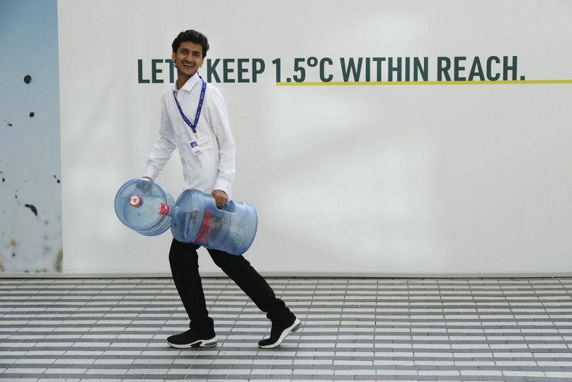 Mężczyzna niesie pojemniki z wodą przed szczytem klimatycznym ONZ COP28, listopad 2023 r