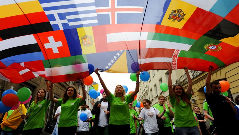 Młodzi ludzie niosą sztandar z flagami krajów europejskich podczas corocznej parady na cześć Roberta Schumanna w Warszawie, maj 2013