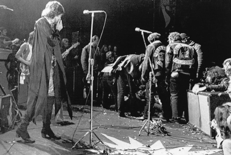 Mick Jagger przestaje występować na festiwalu Altamont Rock w Livermore w Kalifornii, 8 grudnia 1969 r., podczas gdy Hells Angels przechodzą przez scenę podczas walki wręcz, aby pomóc innym motocyklistom.