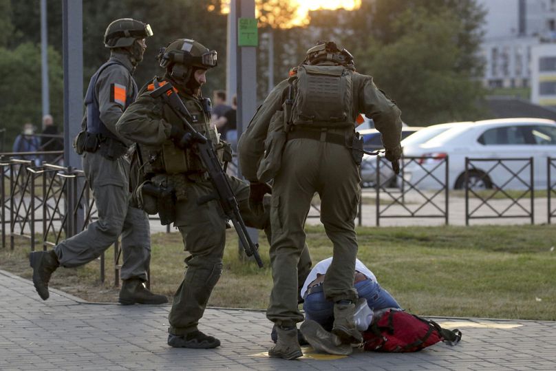 Policjanci kopią demonstranta podczas masowego protestu po wyborach prezydenckich w Mińsku, sierpień 2020 r