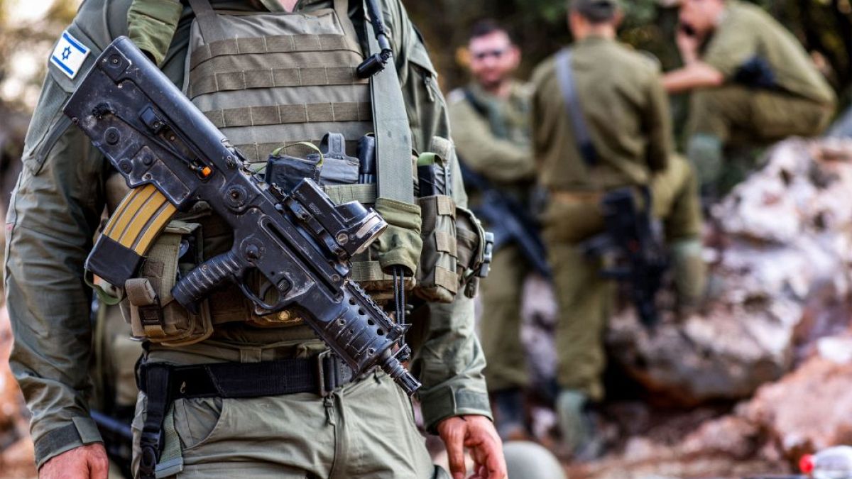 An Israeli army soldier - not one of the accused - stands with an assault rifle hanging across his chest