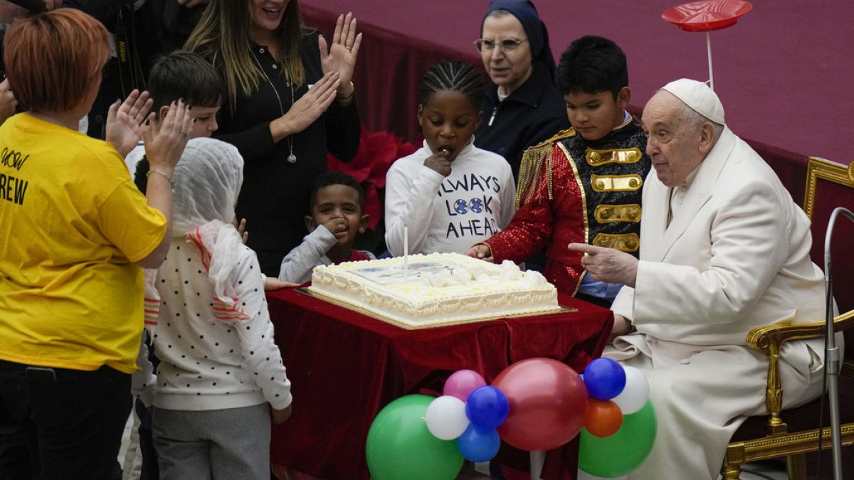 Pope Francis blows a candle on a cake as he celebrates his birthday