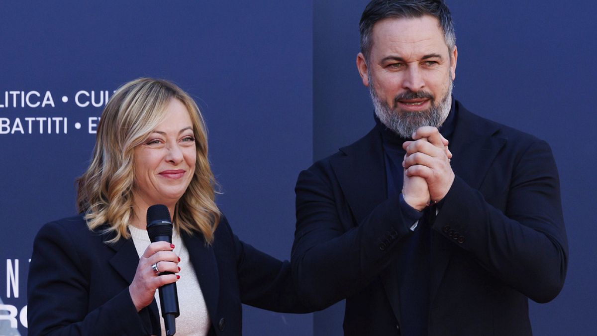 Leader of the Spanish far-right VOX party Santiago Abascal, right, stands on the stage with Italy