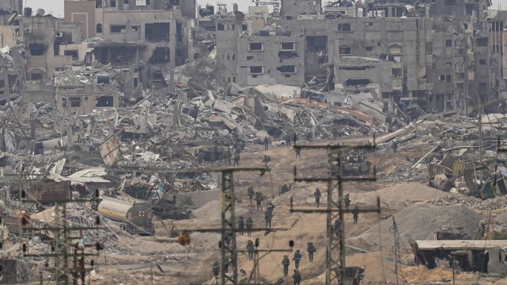 Israeli troops walk in the Gaza Strip as seen from southern Israel, Thursday, Dec. 21, 2023.