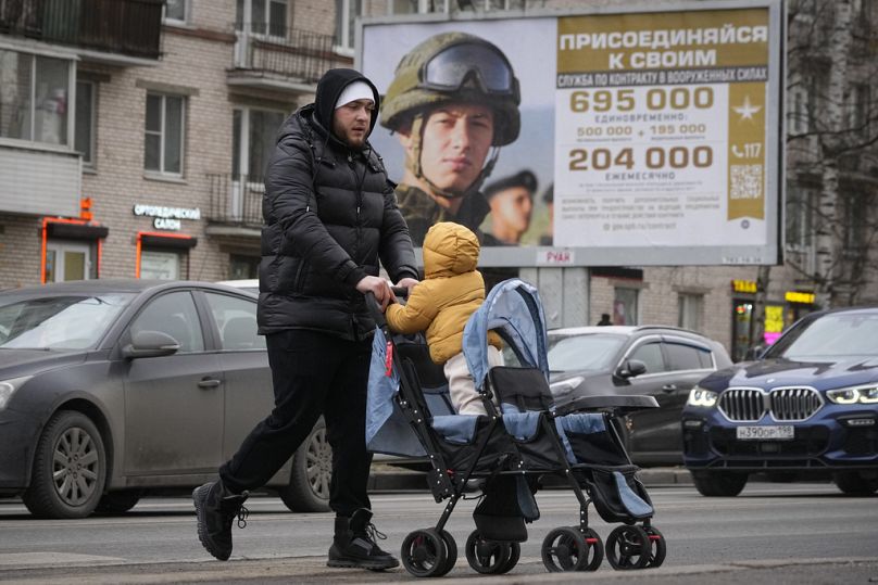 Mężczyzna przechodzi obok billboardu reklamowego promującego kontraktową służbę wojskową w armii rosyjskiej w Petersburgu, listopad 2023 r.