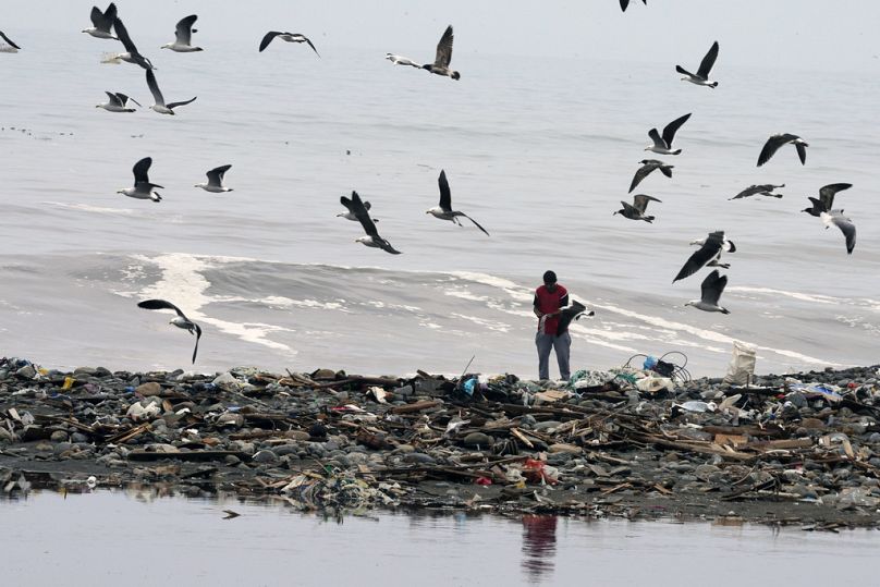 Mężczyzna spaceruje po plaży Marquez, gdzie śmieci pokrywają brzegi rzeki Chillon i Oceanu Spokojnego w Callao, Peru, sierpień 2023 r.