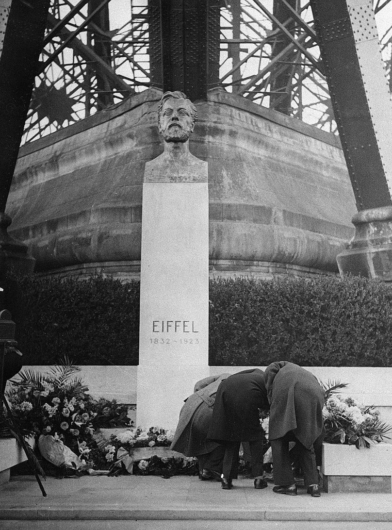 Niezidentyfikowani krewni francuskiego inżyniera Gustave’a Eiffela składają kwiaty pod jego pomnikiem przed Wieżą Eiffla w Paryżu – 15 grudnia 1932 r.