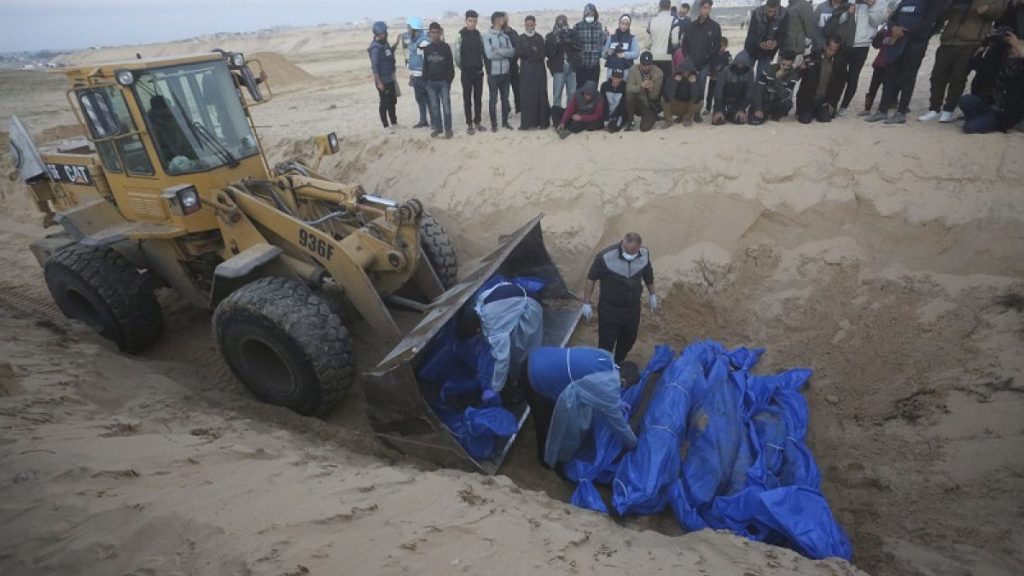 Bulldozer unloads the bodies of Palestinians killed in the north of the Gaza Strip and turned over by the Israeli military during a mass funeral in Rafah, Tuesday, Dec. 26.