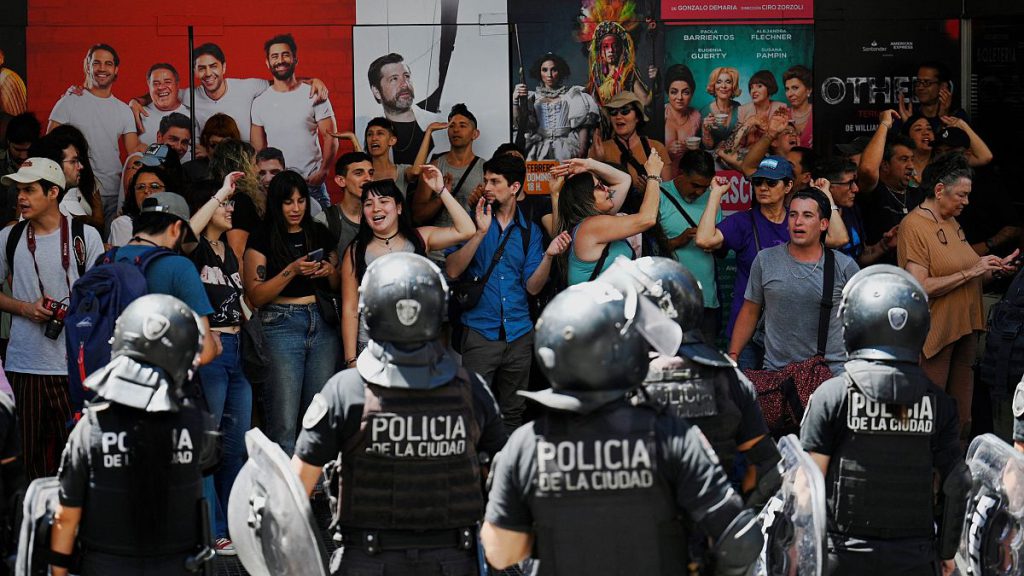 Protesters shouting harangues are guarded by riot police after a demonstration called by Argentina